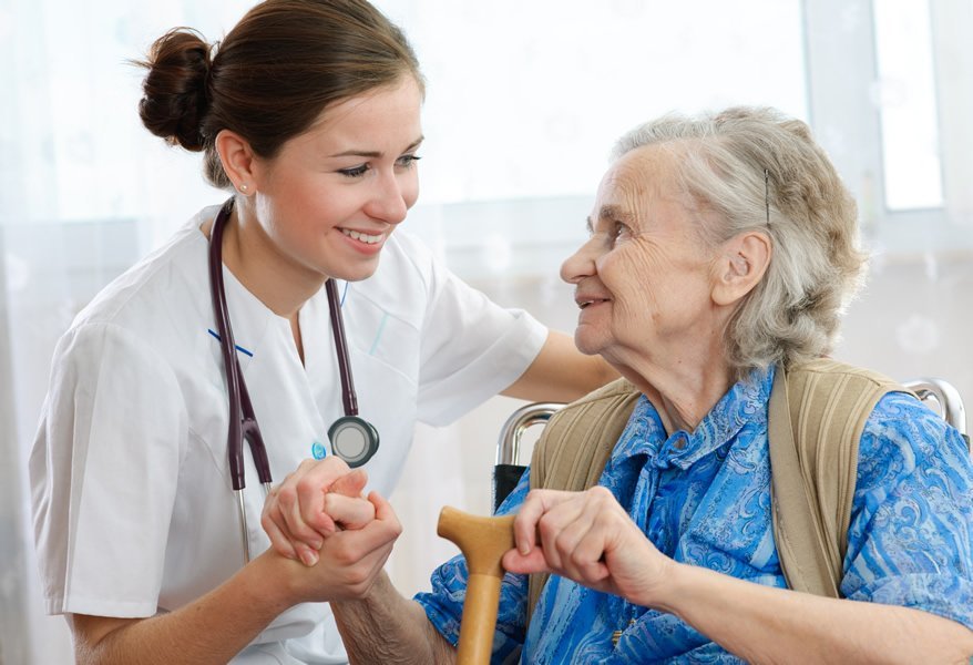 Woman with Stethescope holds elderly woman's hand